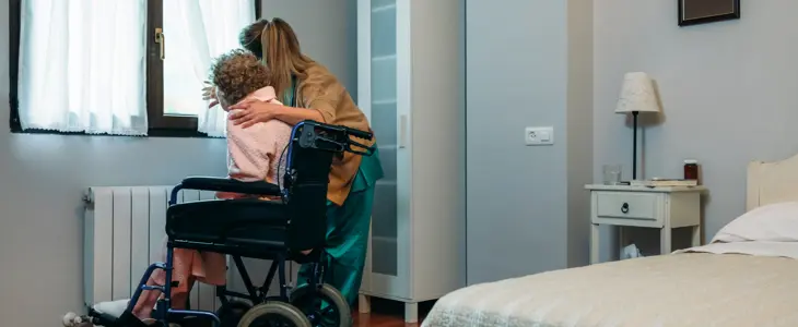 Caregiver showing the view through the window to an elderly patient in a wheelchair